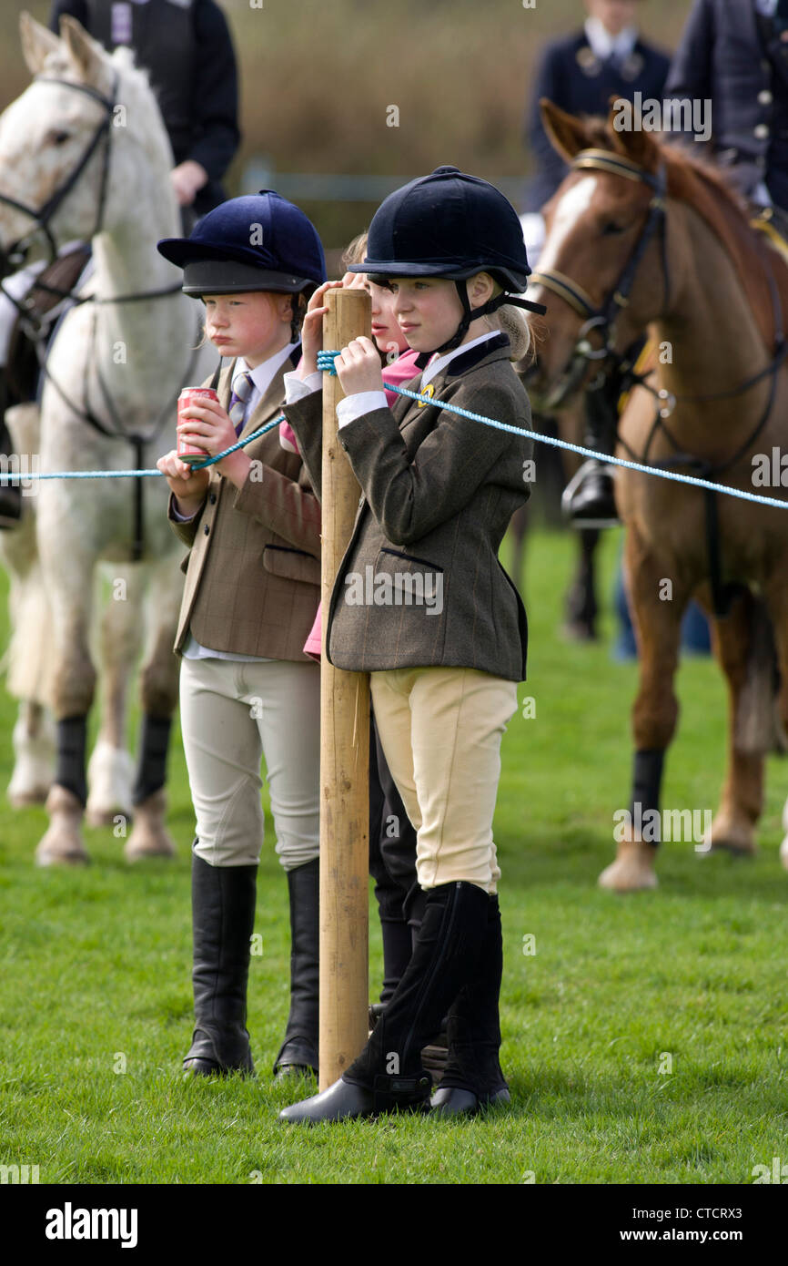 Two young equestrian riders watching other competitors taking part in a schools equestrian horse riding event. Stock Photo