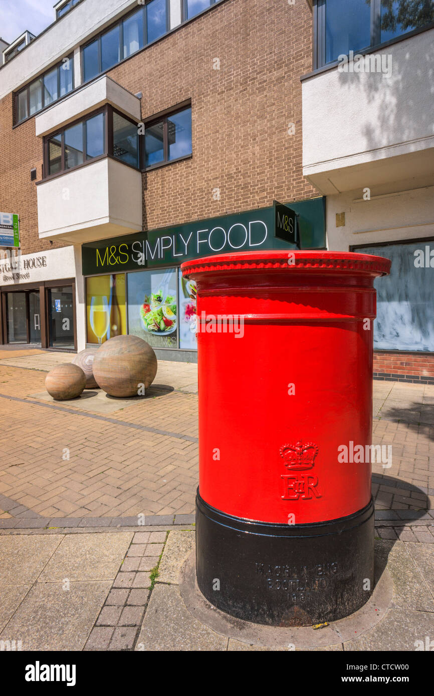 a red post box on a street in the town of warwick, in the UK. There are