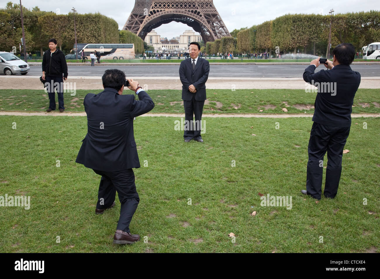 Chinese tourist pose to photos in Parc du Champ de Marc - Field of Mars near the Eiffel Tower in Paris, France. Stock Photo