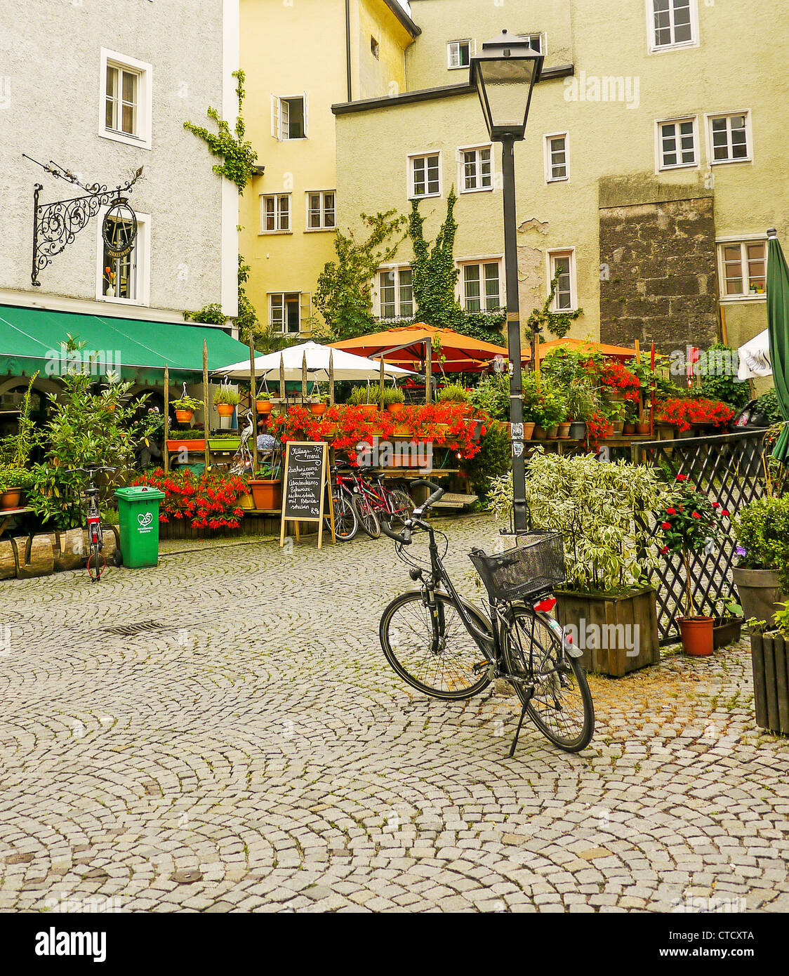 A bicycle in front a lap standard in a cobbled courtyard with a florist and a cafe in Saltzburg, Austria Stock Photo