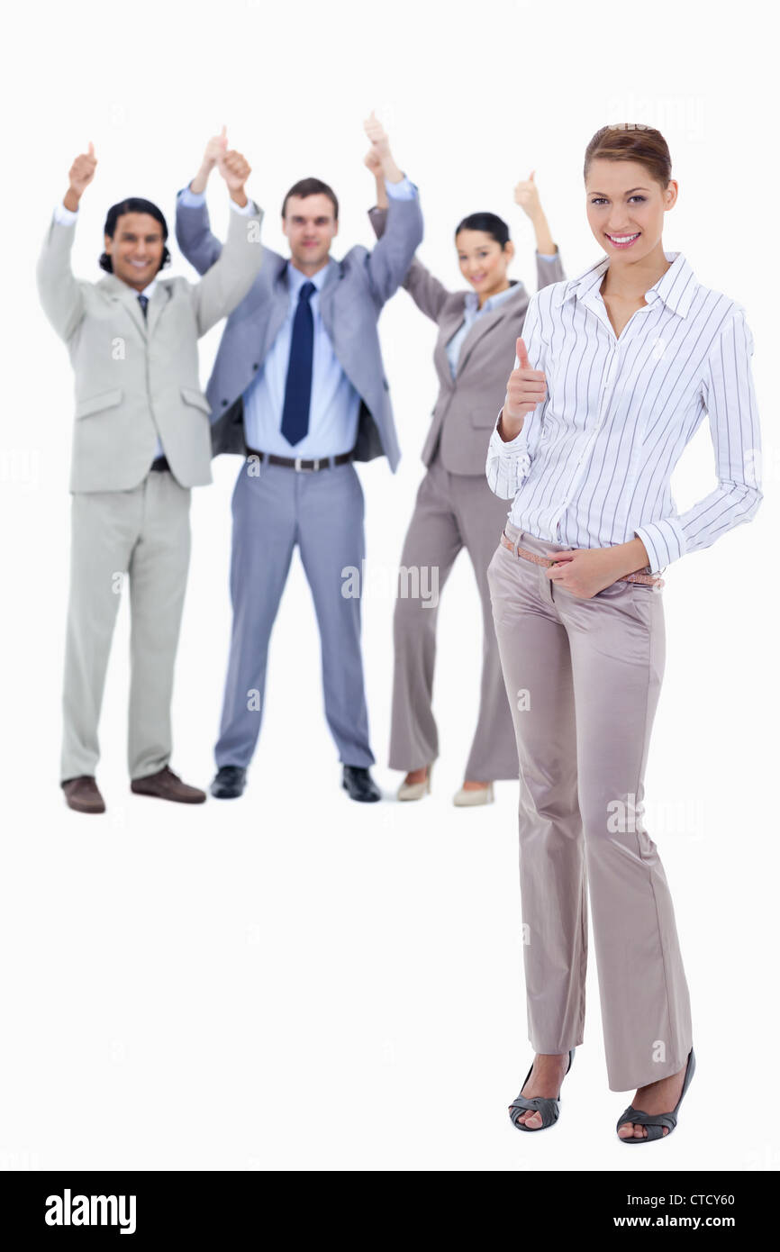 Secretary in foreground and business people with their thumbs up Stock Photo