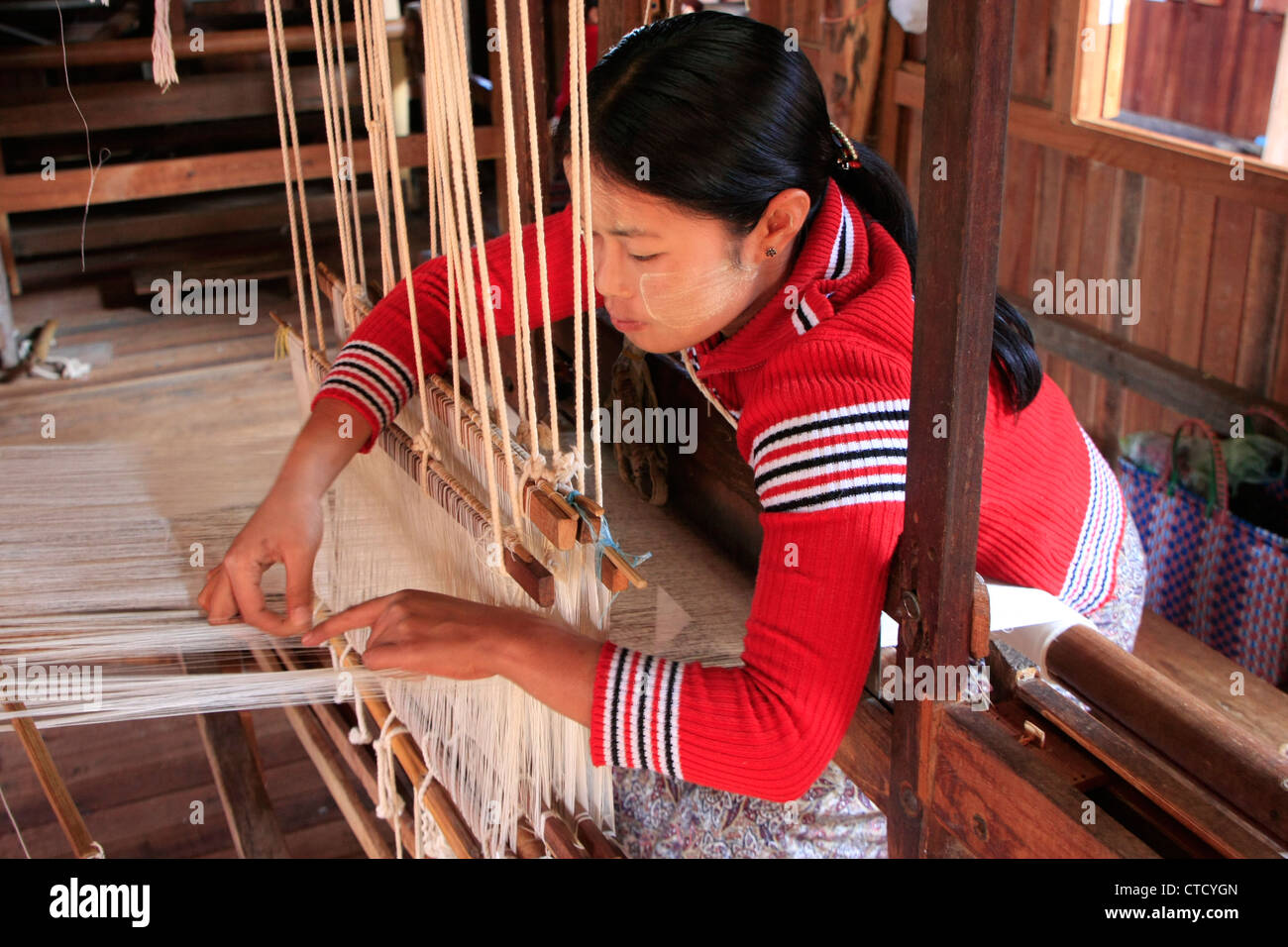 Young burmese woman weaving on a loam, Inle lake, Shan state, Myanmar, Southeast Asia Stock Photo