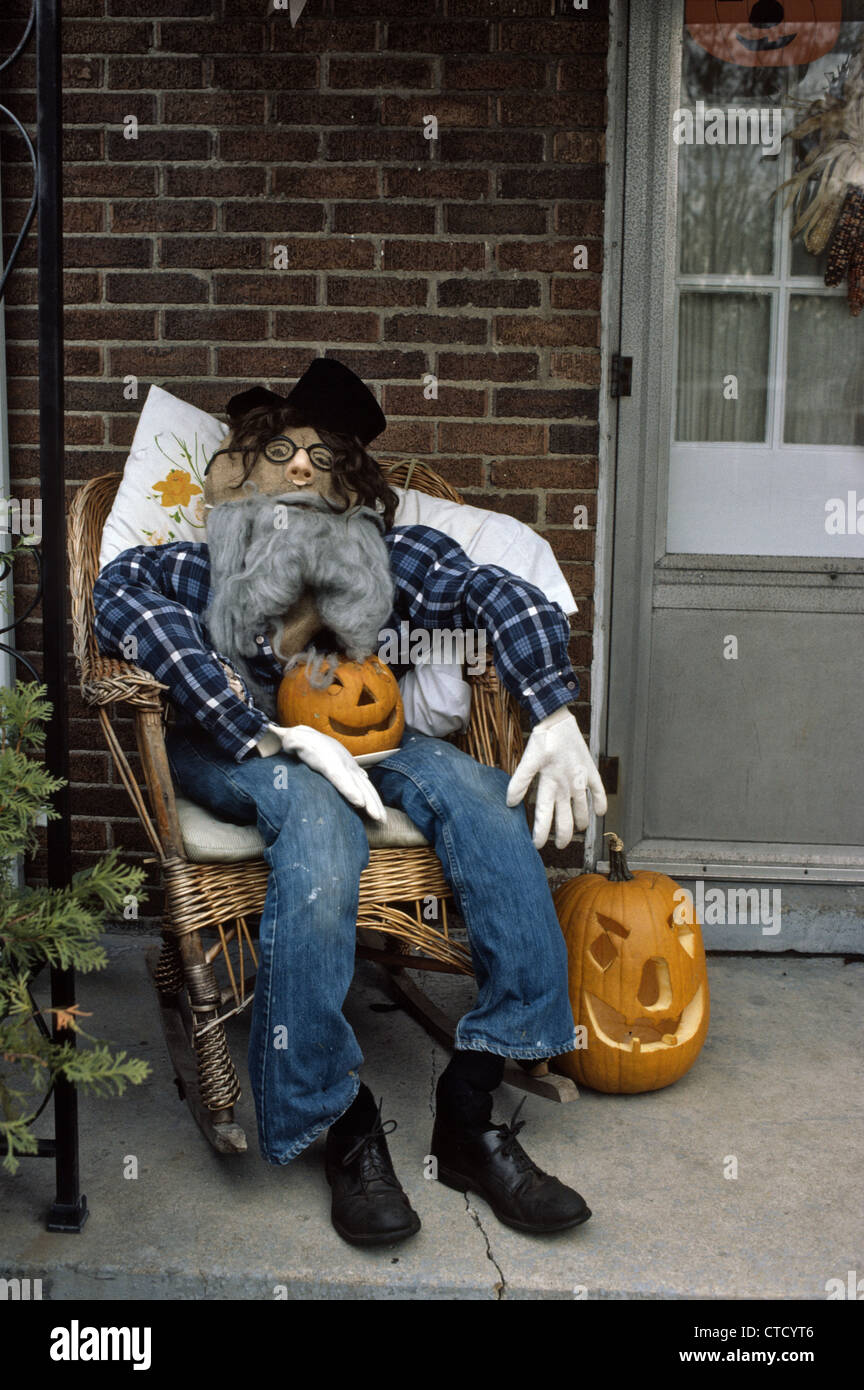 Stuffed Dummy Holding Jack o lantern Carved Pumpkin On Porch Of An