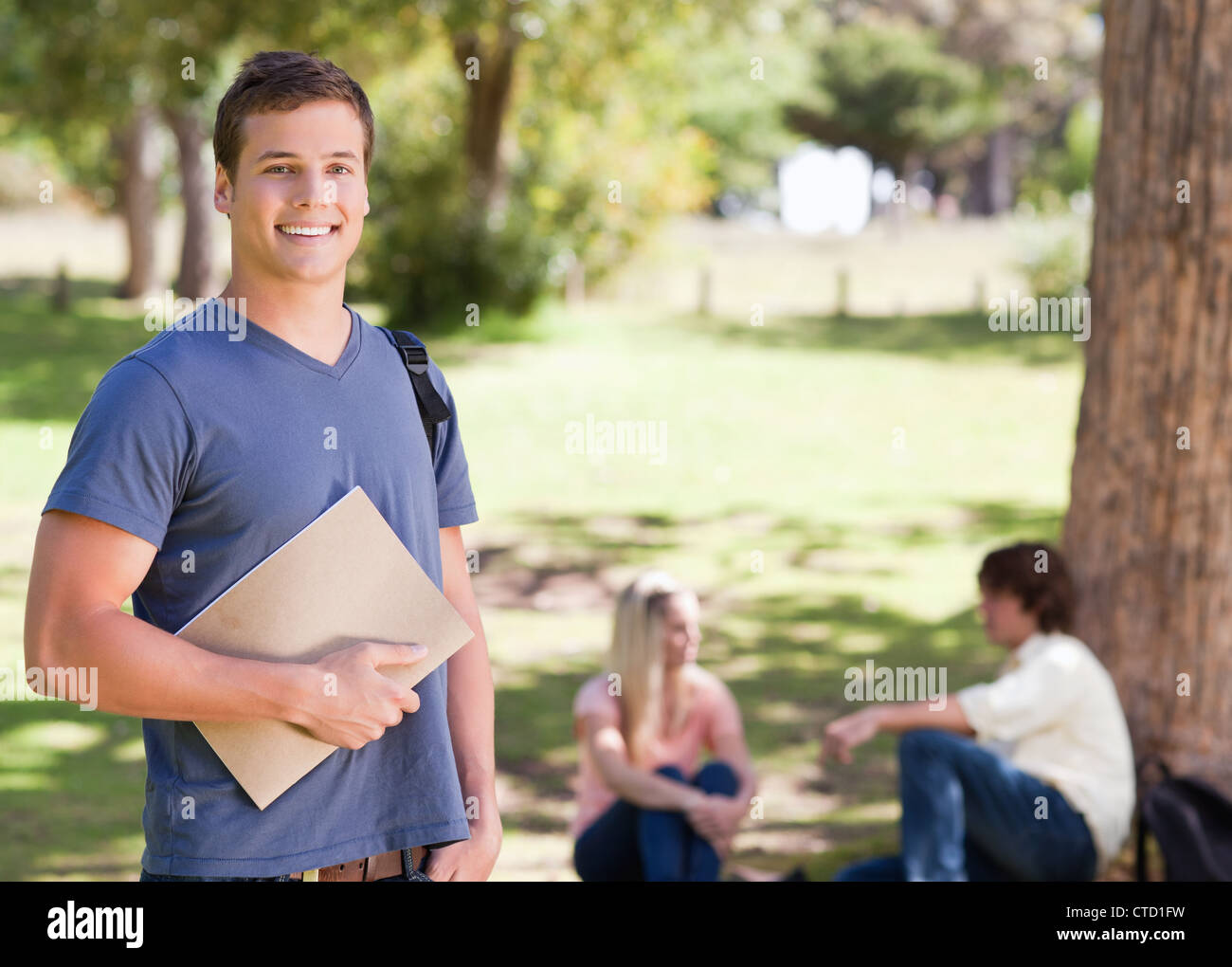 Portrait of a smiling student holding a textbook Stock Photo - Alamy