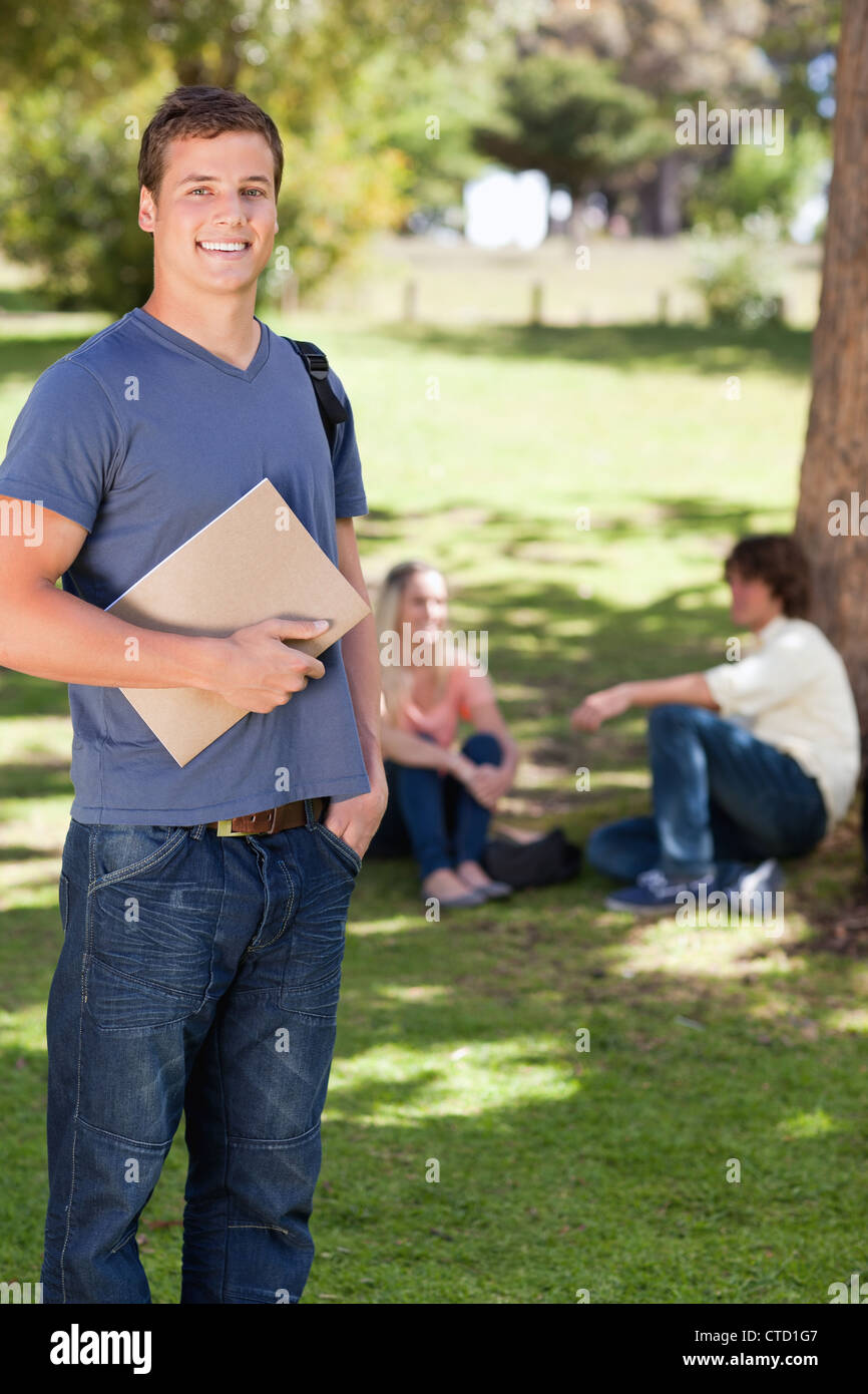 Student smiling while holding a textbook Stock Photo - Alamy