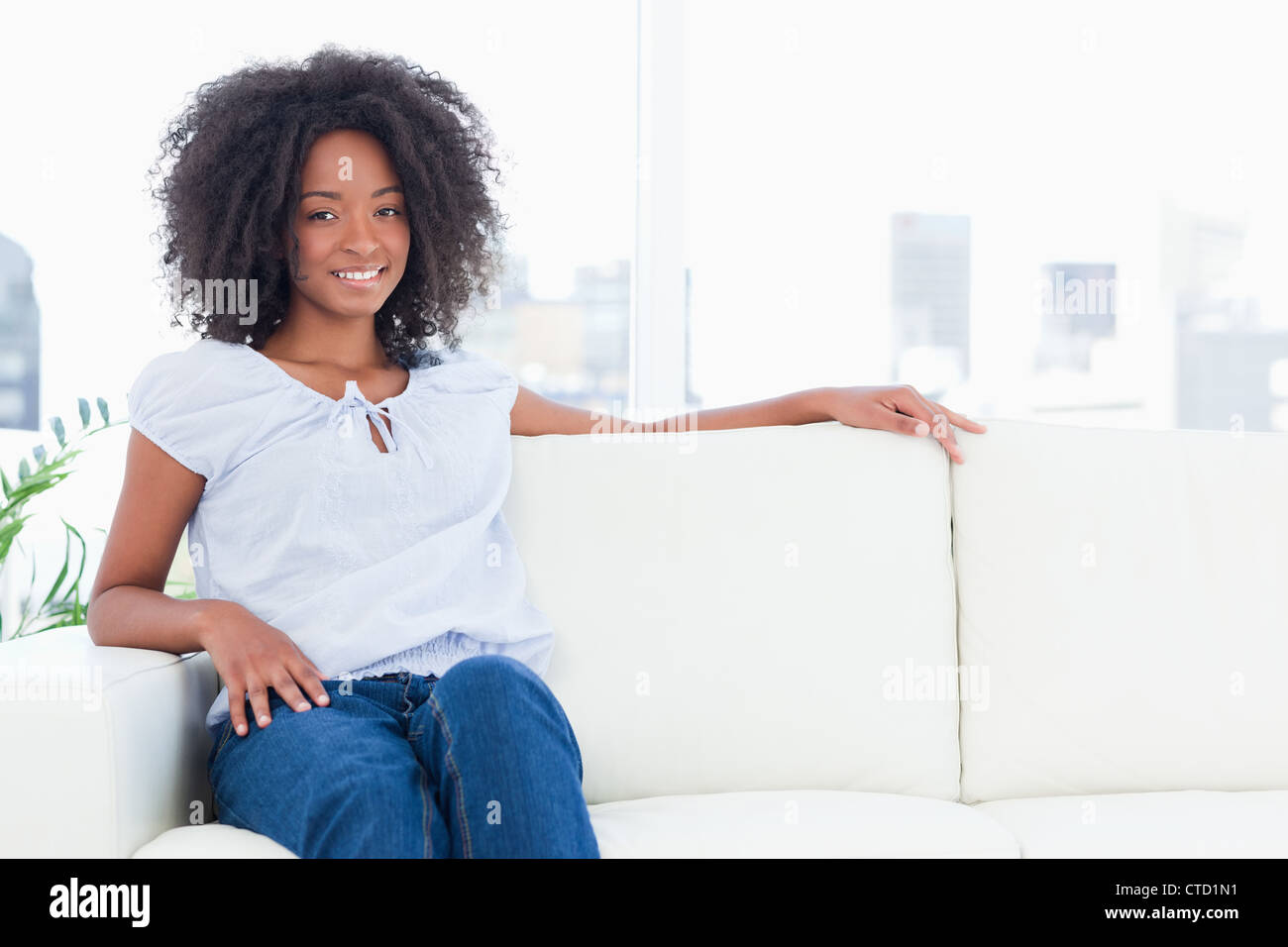Woman with a sitting on a sofa Stock Photo - Alamy