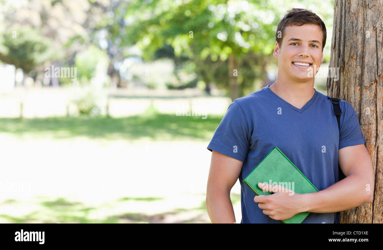 Portrait of a smiling muscled student holding a textbook Stock Photo ...