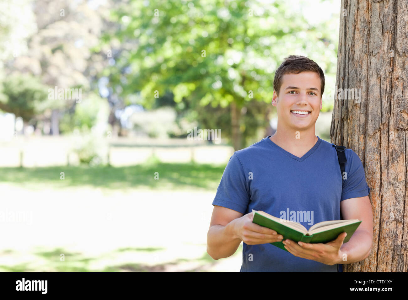 Portrait of a smiling toothy student holding a textbook Stock Photo - Alamy