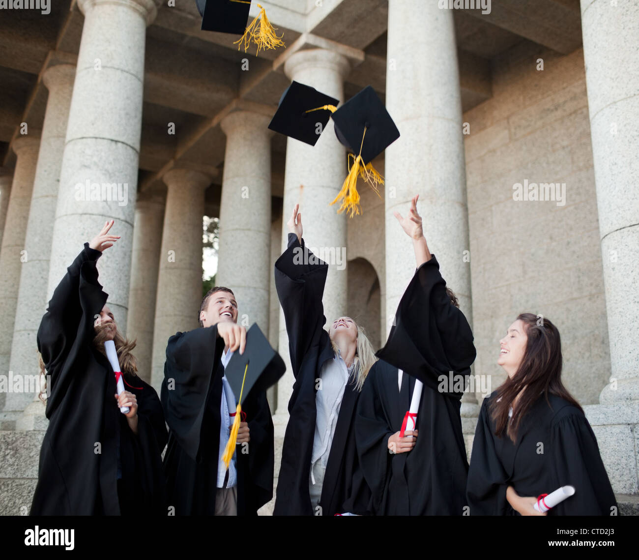 Smiling graduates throwing their hats in the sky Stock Photo Alamy