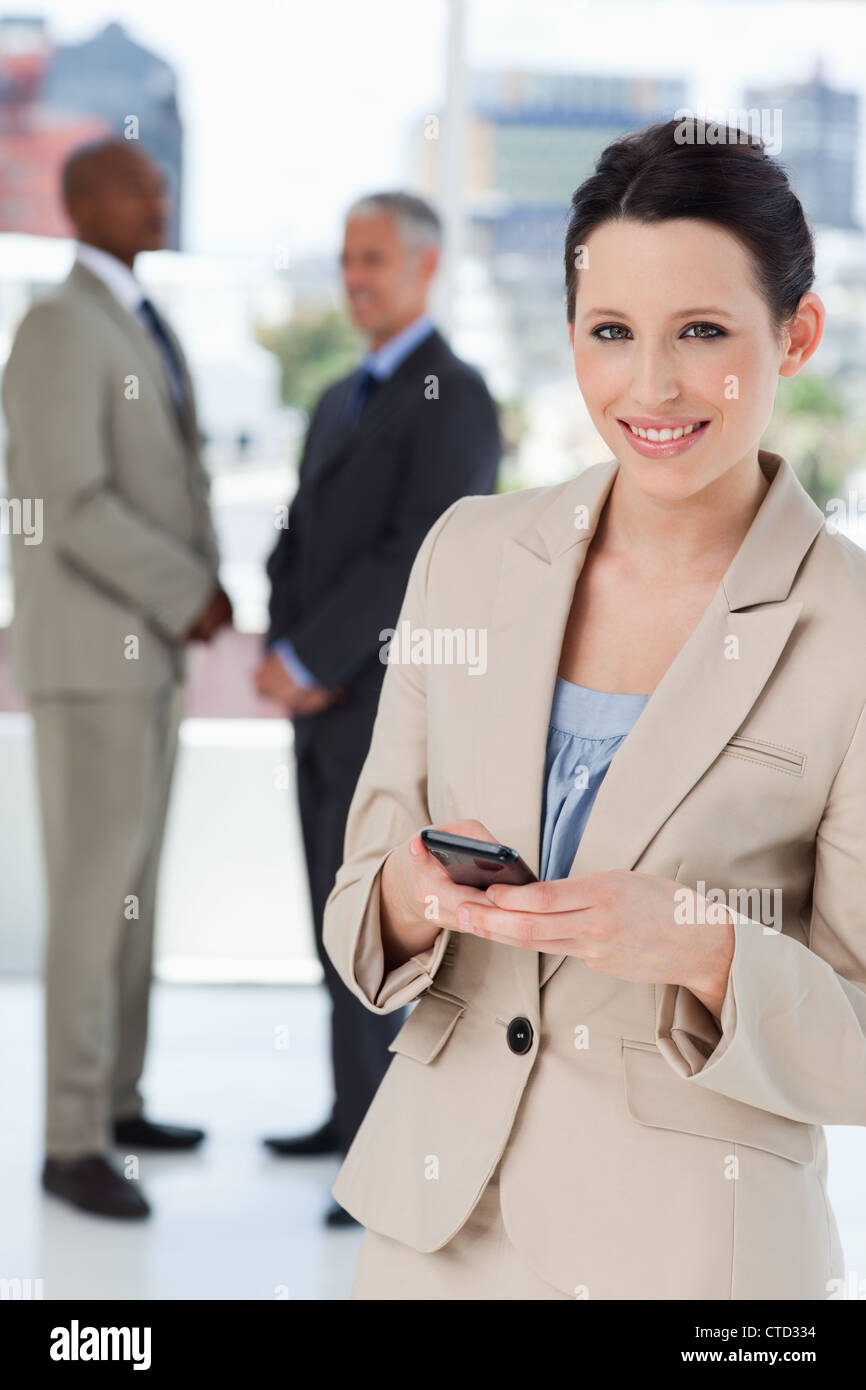 Young secretary standing in front of colleagues while sending a text ...