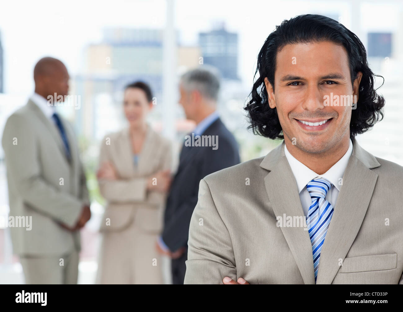 Young smiling executive looking at the camera in front of his team ...