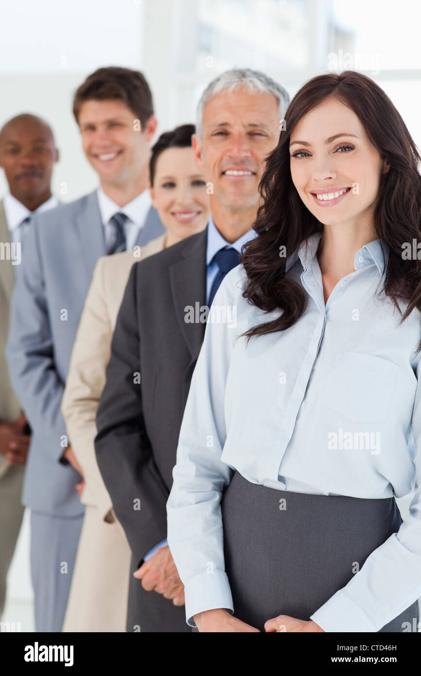 Smiling businesswoman looking confident while being followed by her co-workers Stock Photo