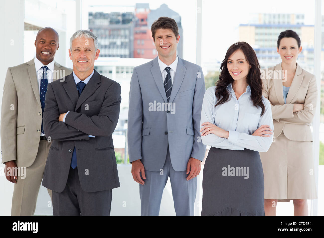 Smiling executive standing in the middle of the bright room among his ...
