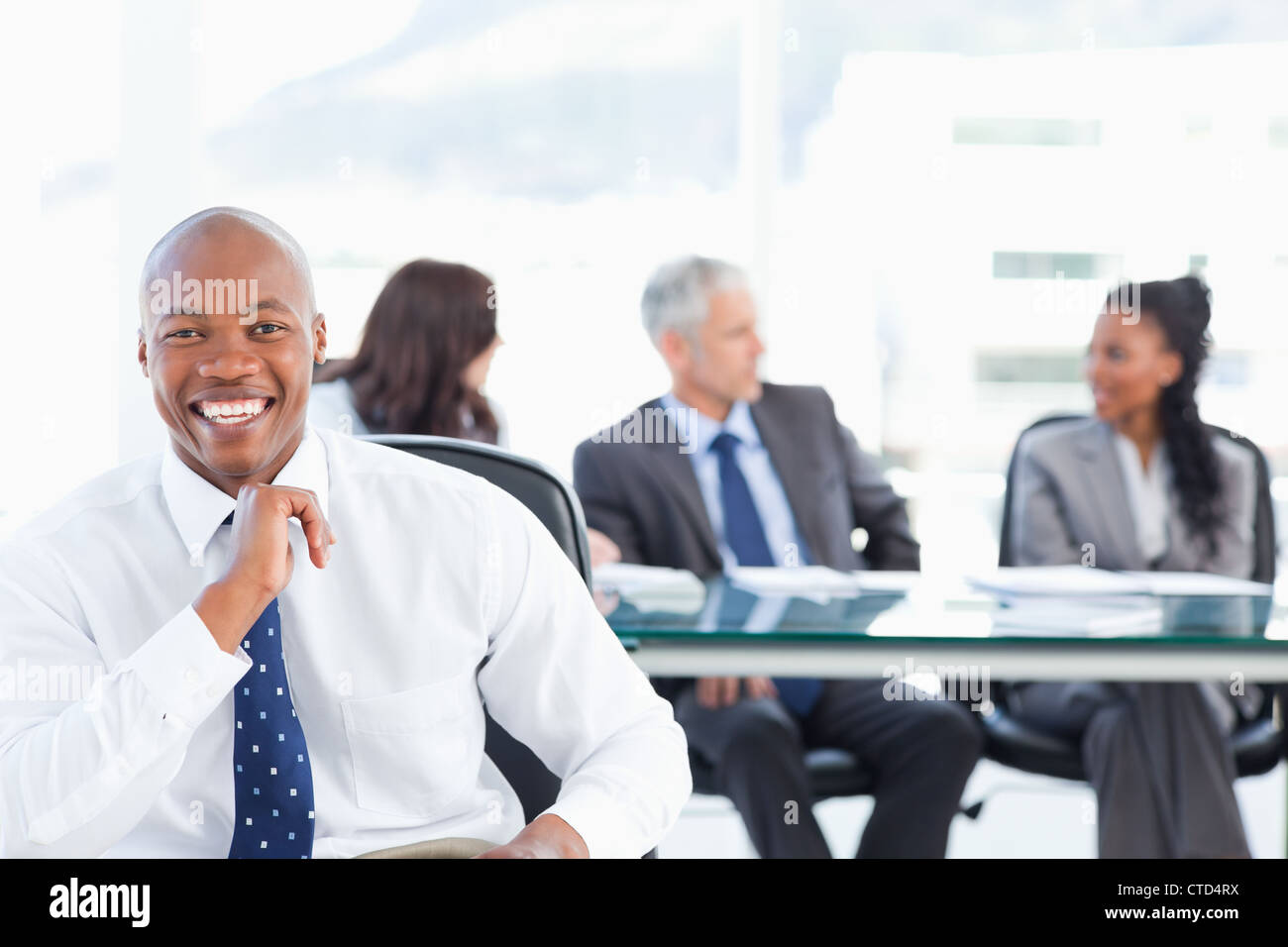 Confident manager laughing while looking at the camera with his team in ...