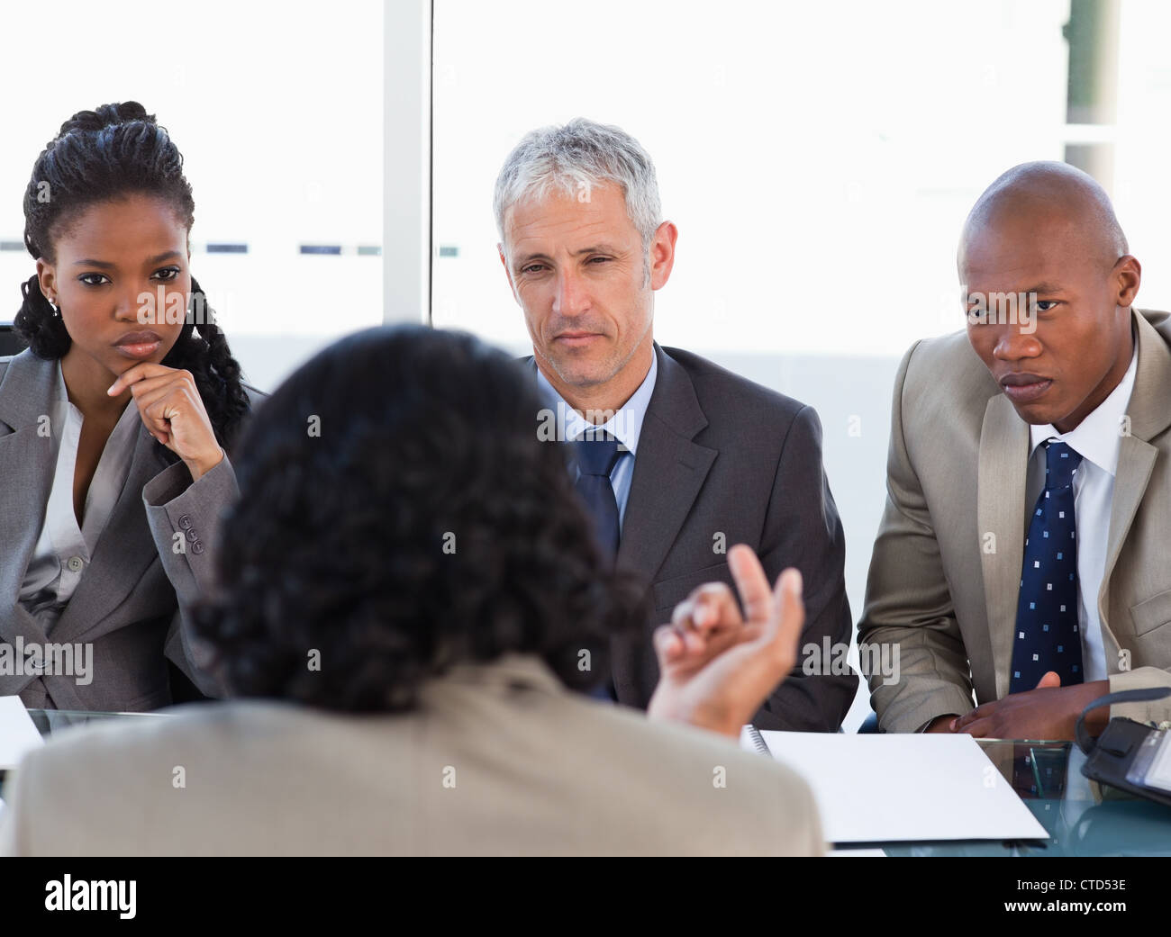 Three business people attentively listening to a speaker in a meeting Stock Photo