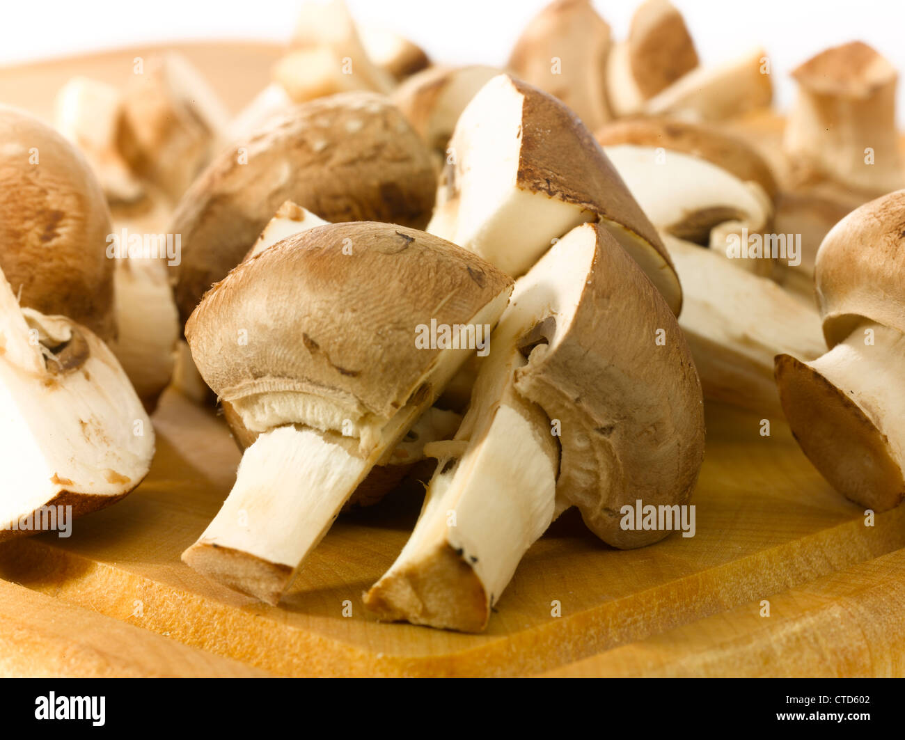 Close-up of champignons cut in half on a wooden cutting board. Stock Photo