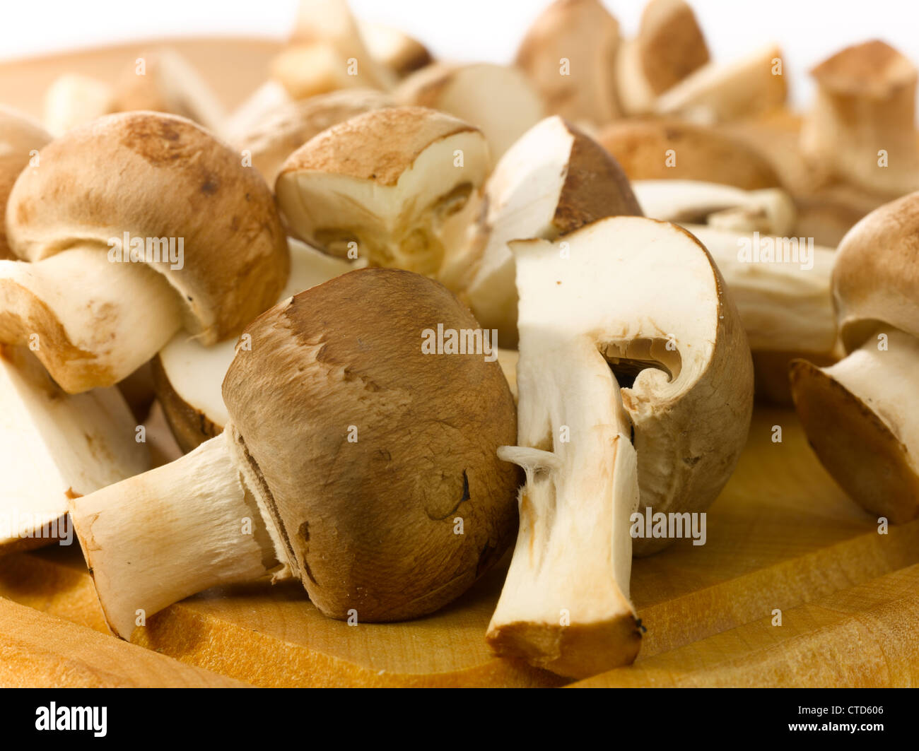 Close-up of champignons cut in half on a wooden cutting board. Stock Photo