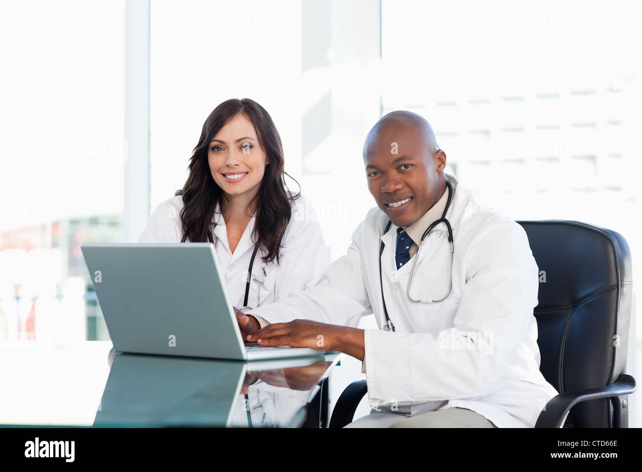 Two nurses working seriously while sitting at the desk in a well lit room Stock Photo