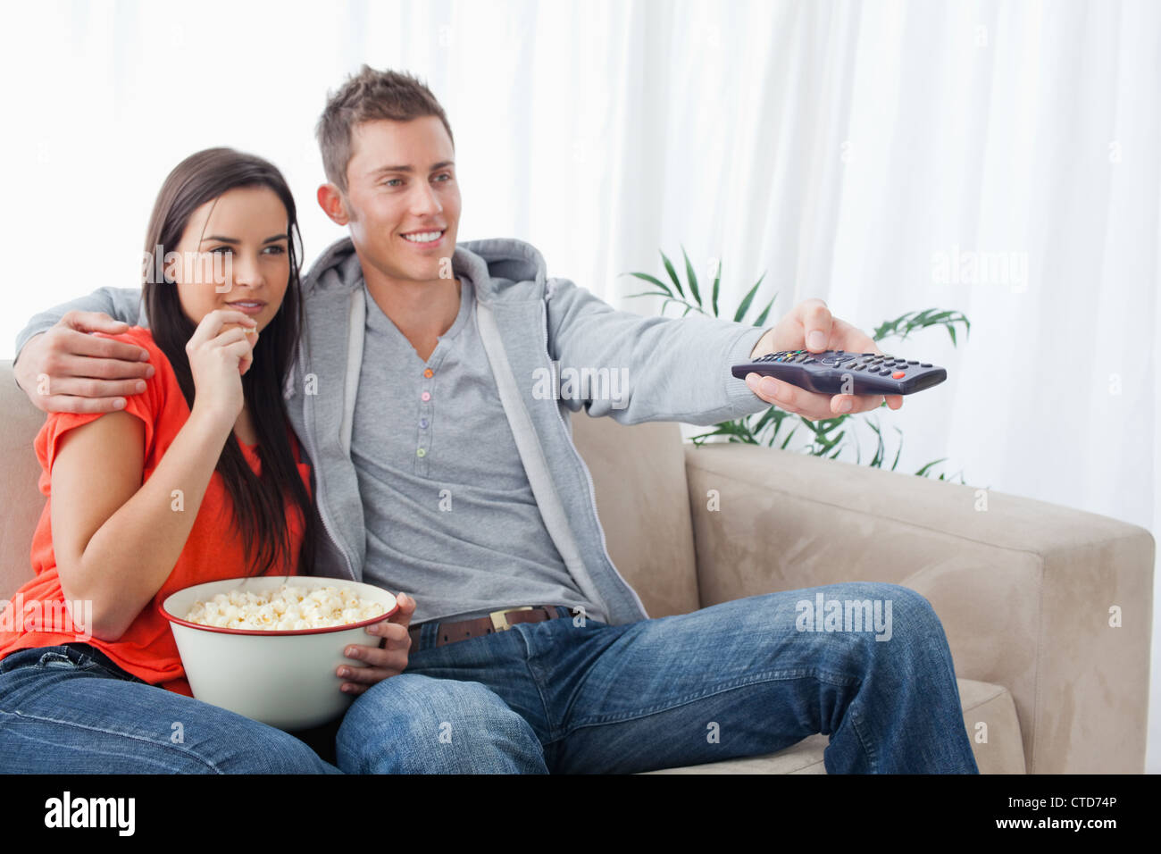 Side view shot of a couple smiling as they change the tv channel Stock Photo