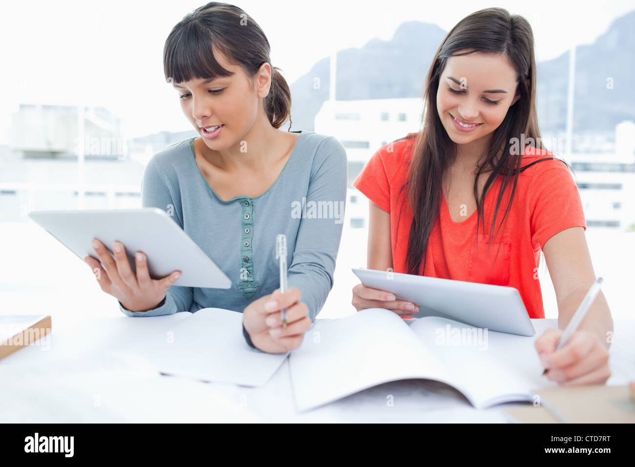 Two girls both using tablet pc's to do their homework Stock Photo