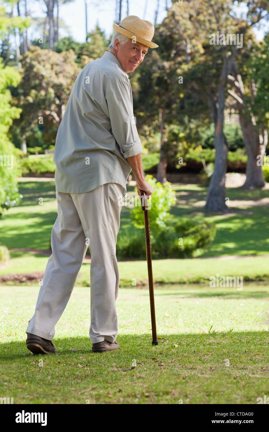 Old man with walking stick and hat looking back at camera Stock Photo -  Alamy