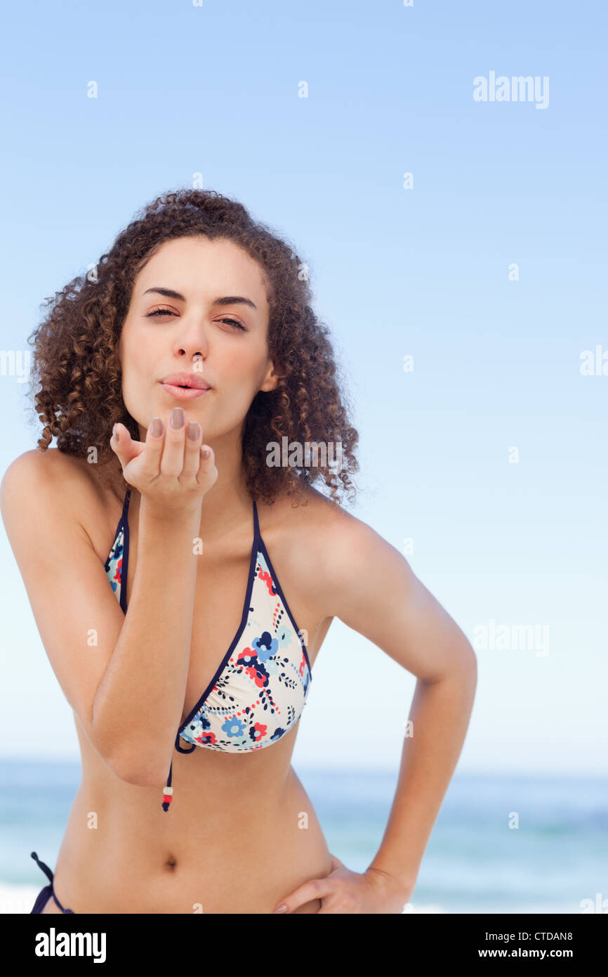 Woman blows a kiss as she rests her hand on her hip Stock Photo
