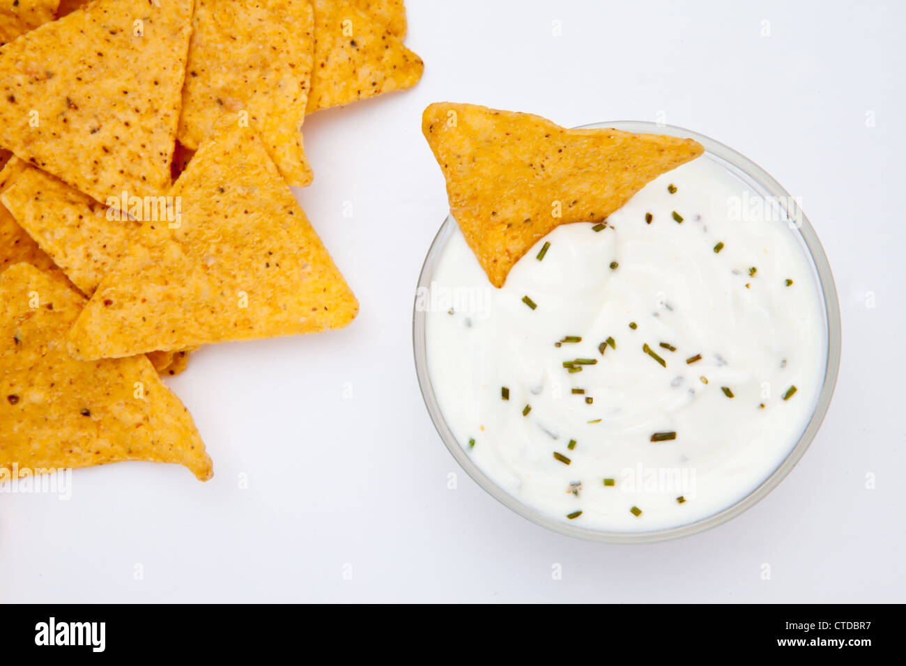 Bowl of dip with herbs with a nacho dipped in it Stock Photo