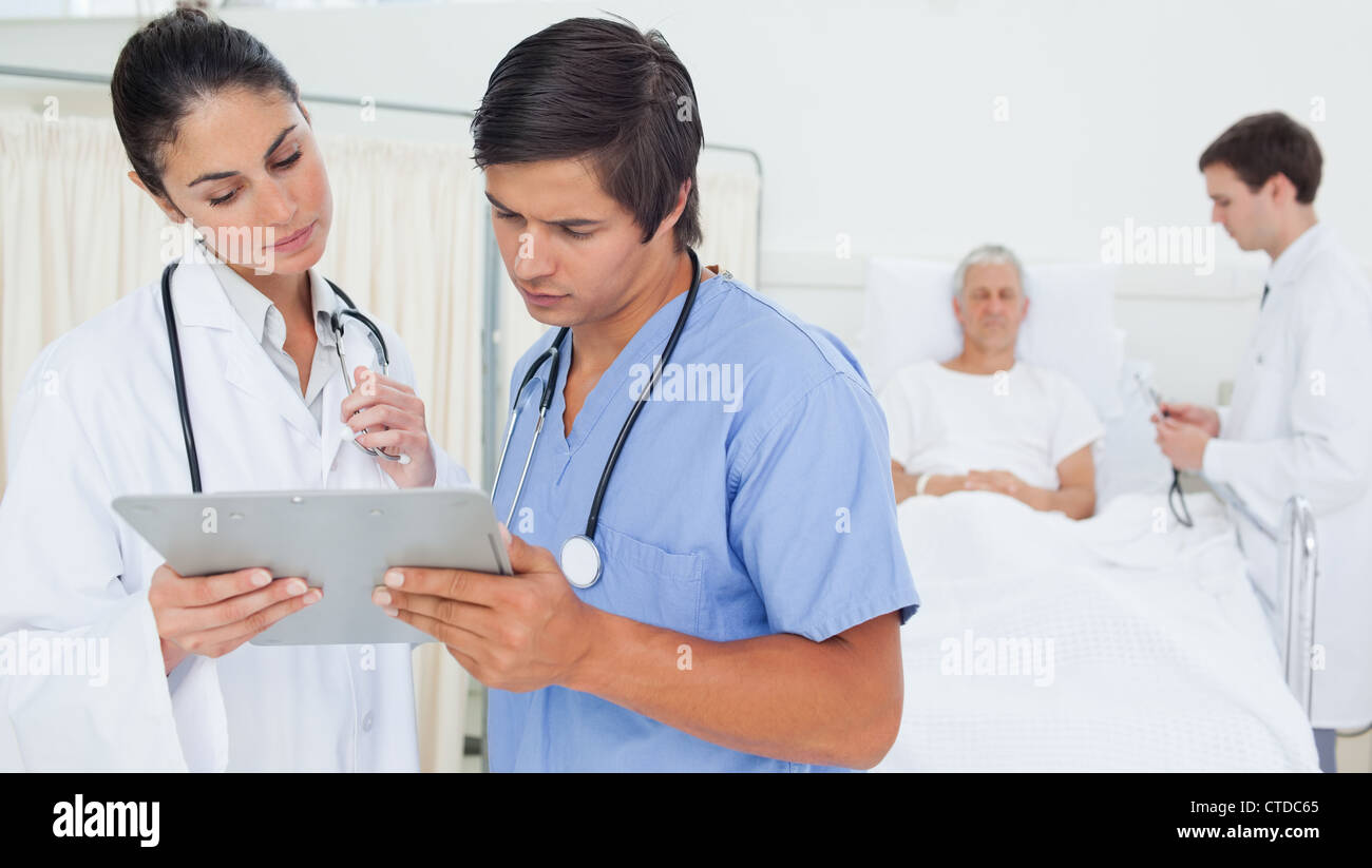 Doctor and an intern examining a clipboard Stock Photo