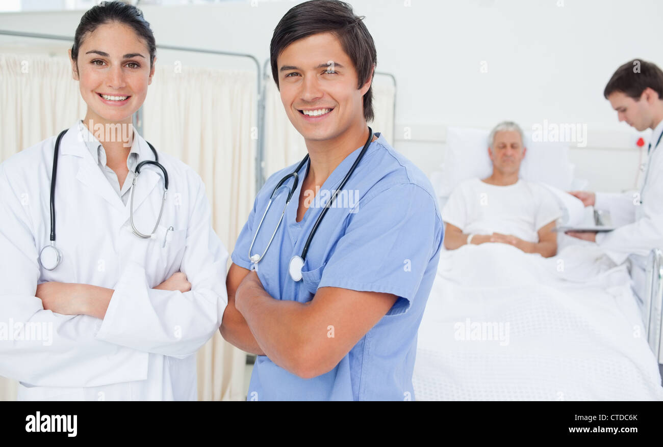 Doctor and an intern smiling while crossing their arms Stock Photo