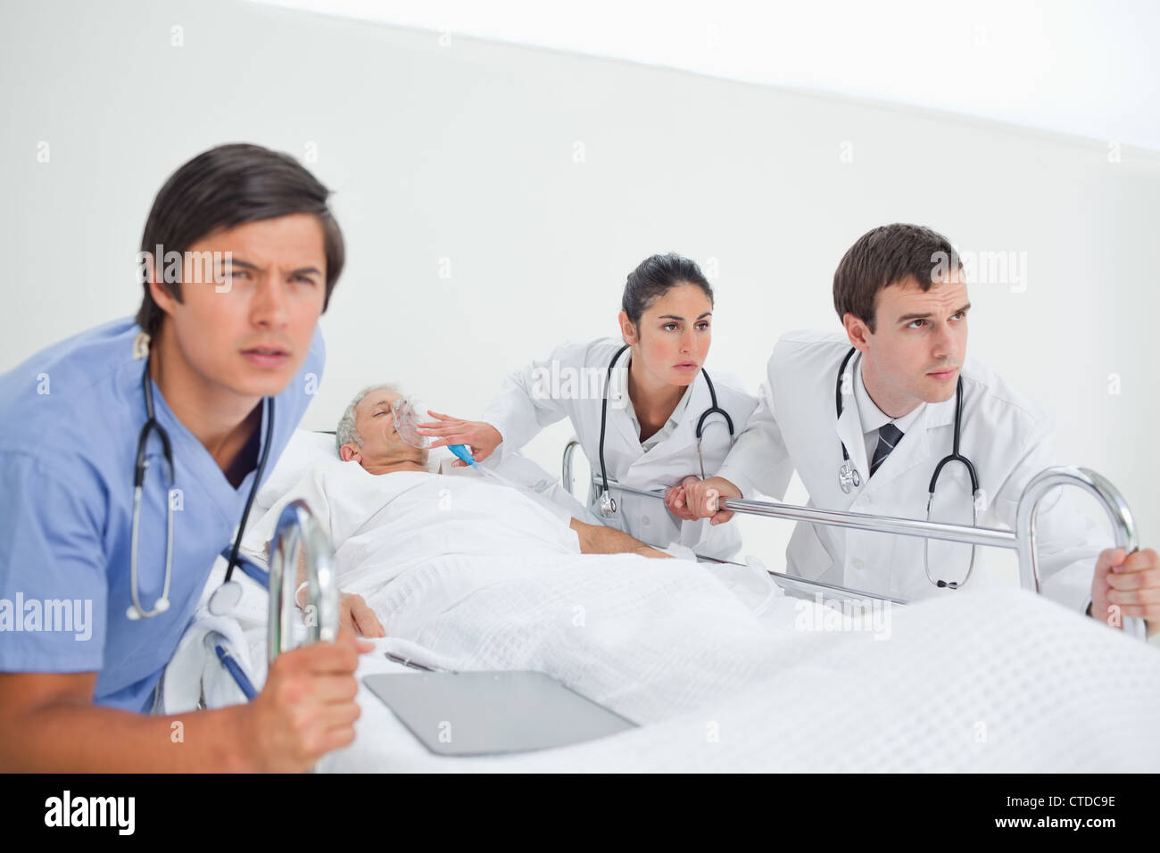 Nurse and two doctors seriously pushing a hospital bed Stock Photo