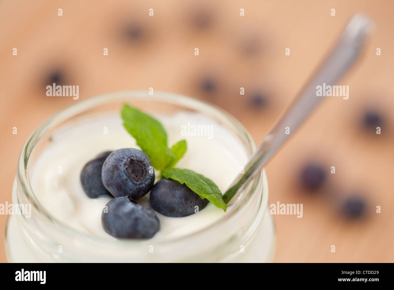Close up of a pot of yoghurt with four leaves and blueberries Stock Photo