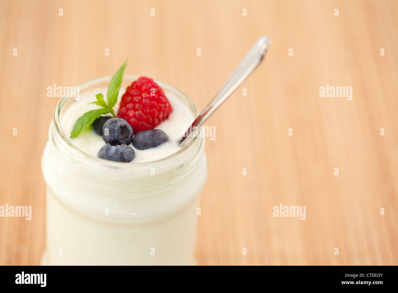 Close up of a pot yogurt with leaves red berries Stock Photo