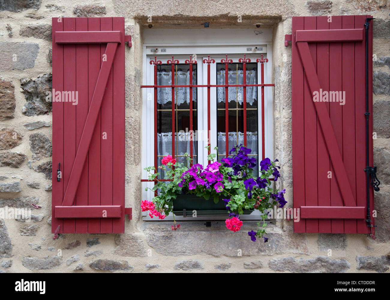 Close up of pretty window with red wooden shutters and flowers in Dinan, Brittany, France Stock Photo