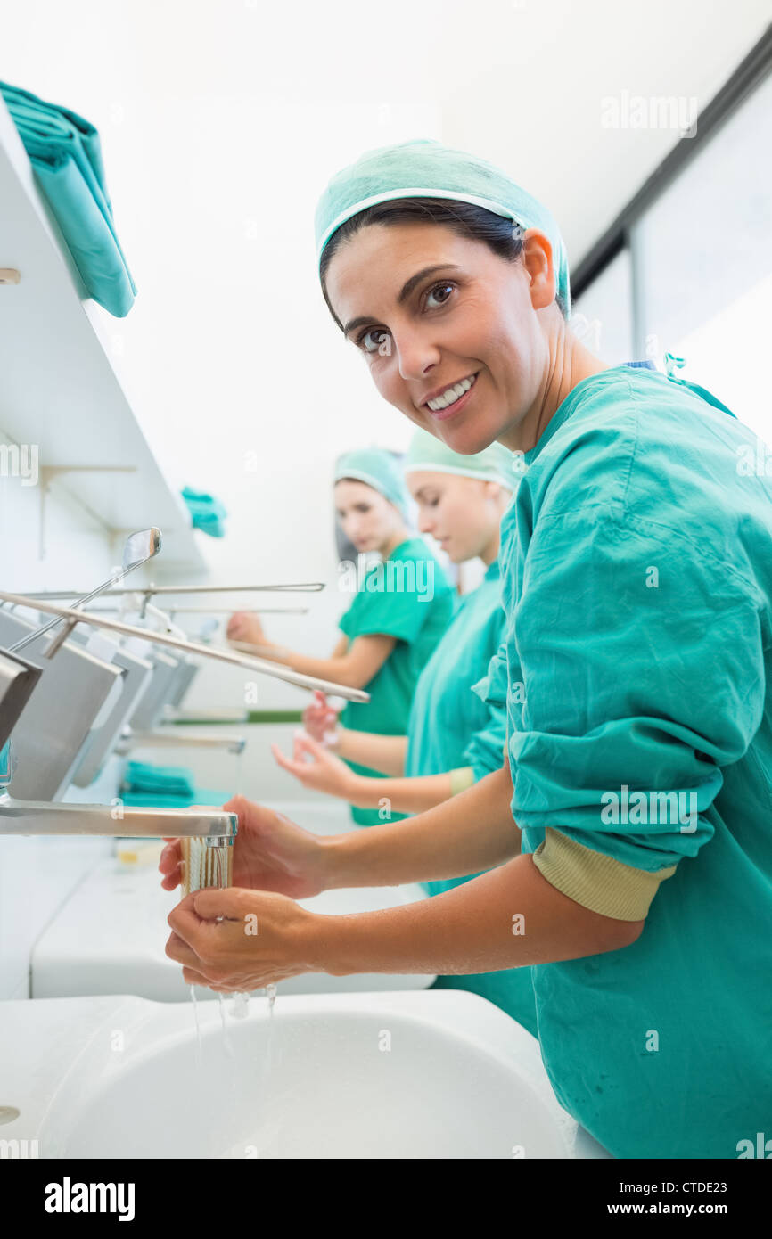 Surgeon rinsing hands while looking at camera Stock Photo