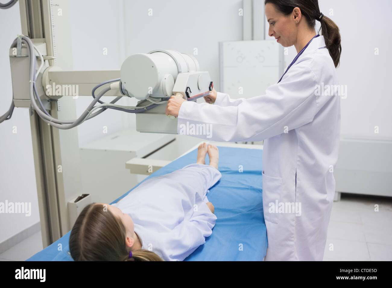 Doctor holding a radiography machine over a patient Stock Photo