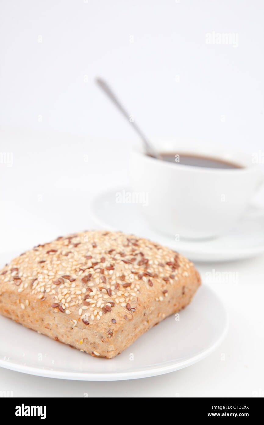Bread bun and a cup of coffee with a spoon on white plates Stock Photo