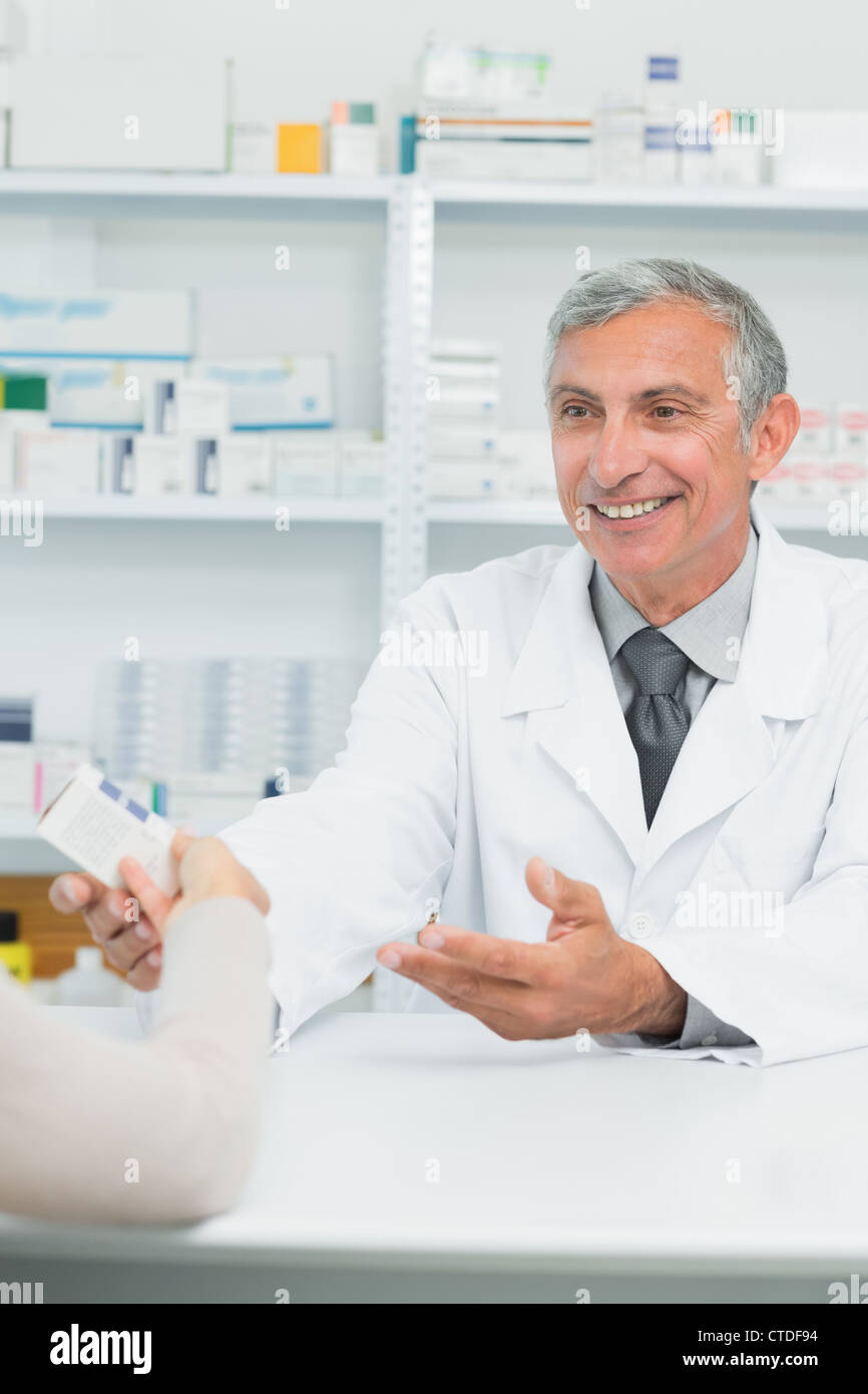 Happy male pharmacist giving pills box to a customer Stock Photo