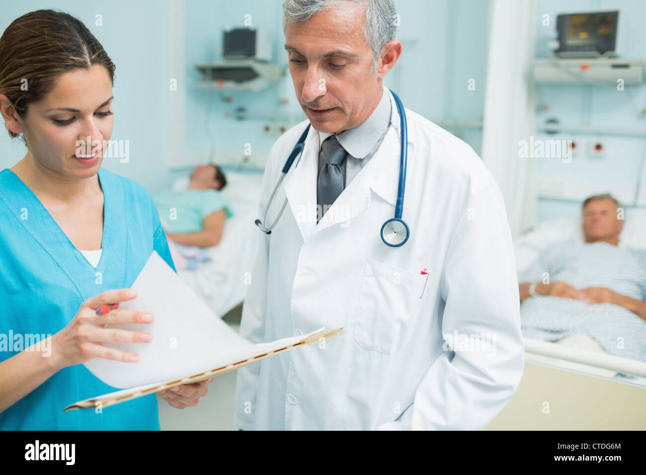 Smiling nurse and a doctor looking at chart in a hospital ward Stock Photo