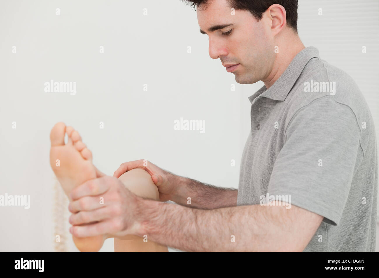 Physio moving his the leg of his patient Stock Photo