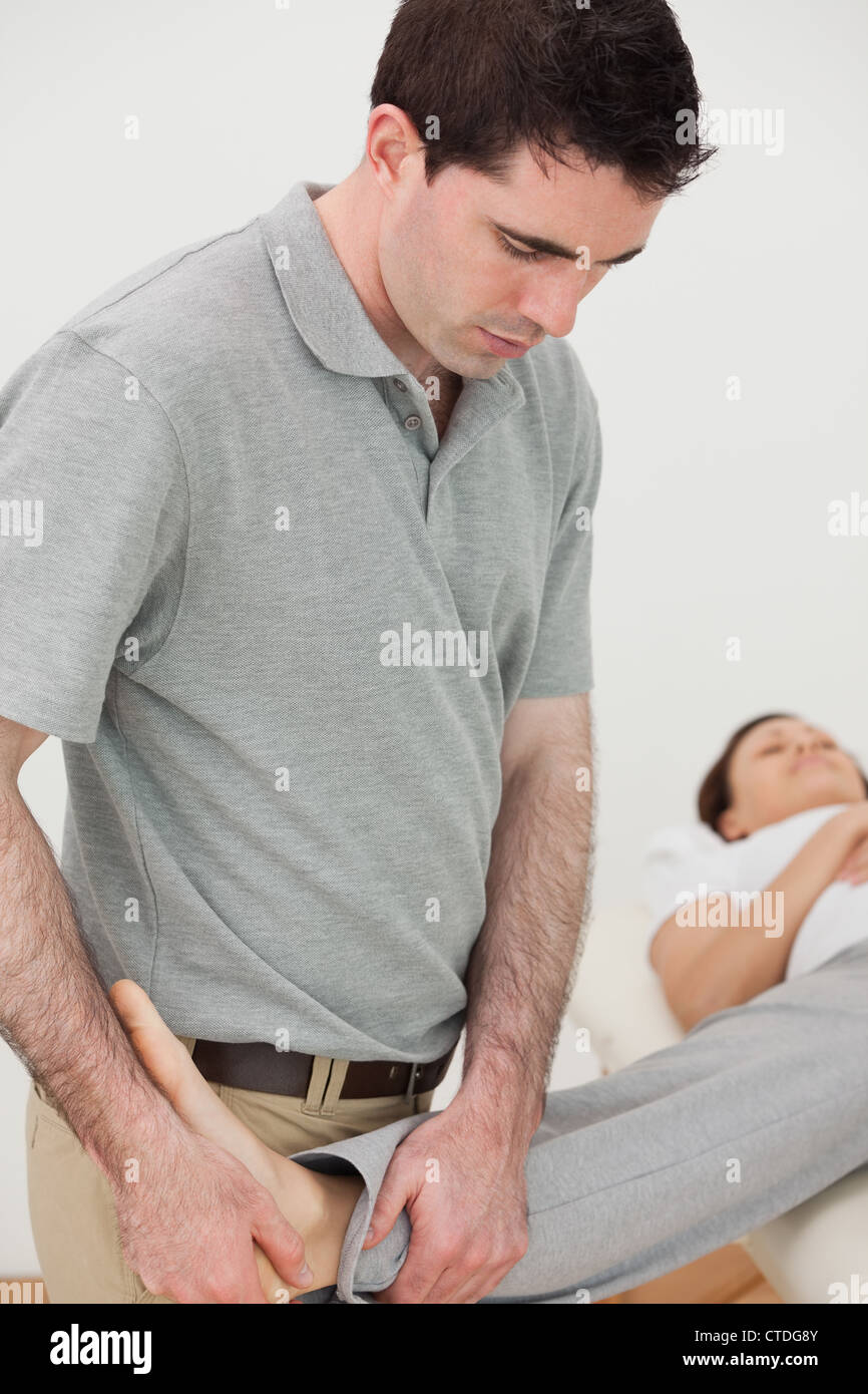 Physio stretching the leg of a woman while looking at her foot Stock Photo