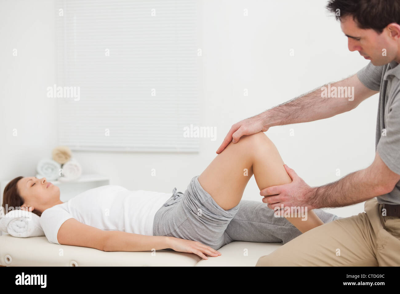 Woman lying while a man manipulating her leg Stock Photo - Alamy