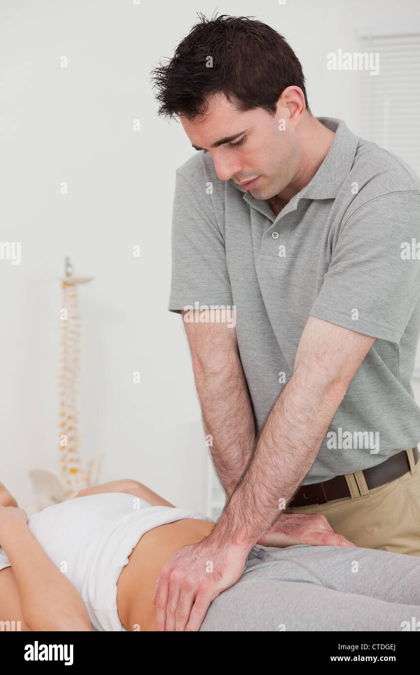 Serious physiotherapist manipulating the pelvis of a patient Stock Photo
