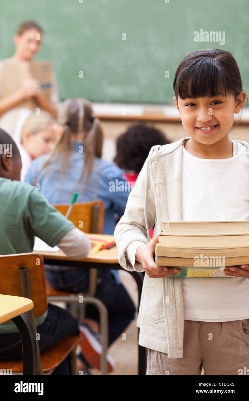 Smiling student standing with pile of books Stock Photo - Alamy