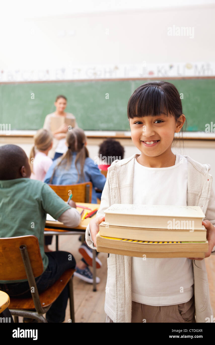 Smiling student holding pile of books Stock Photo - Alamy