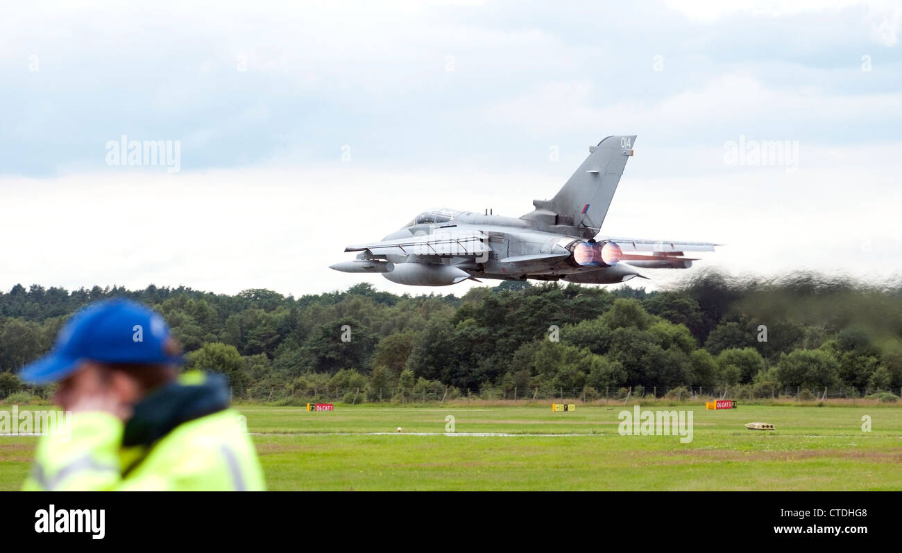 RAF Tornado jet flying very low with afterburners on, and man holding ears Stock Photo