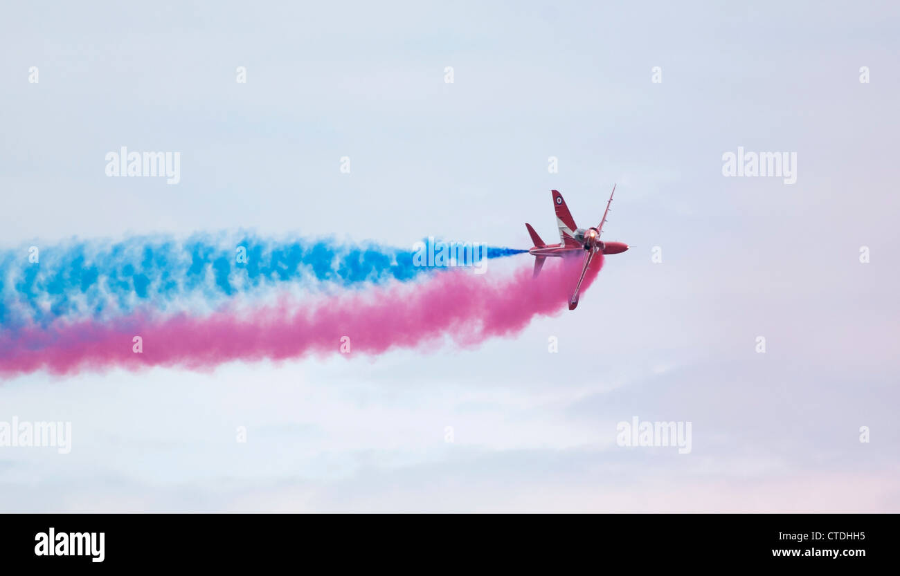 RAF Red Arrows passing close and trailing red and blue smoke Stock Photo