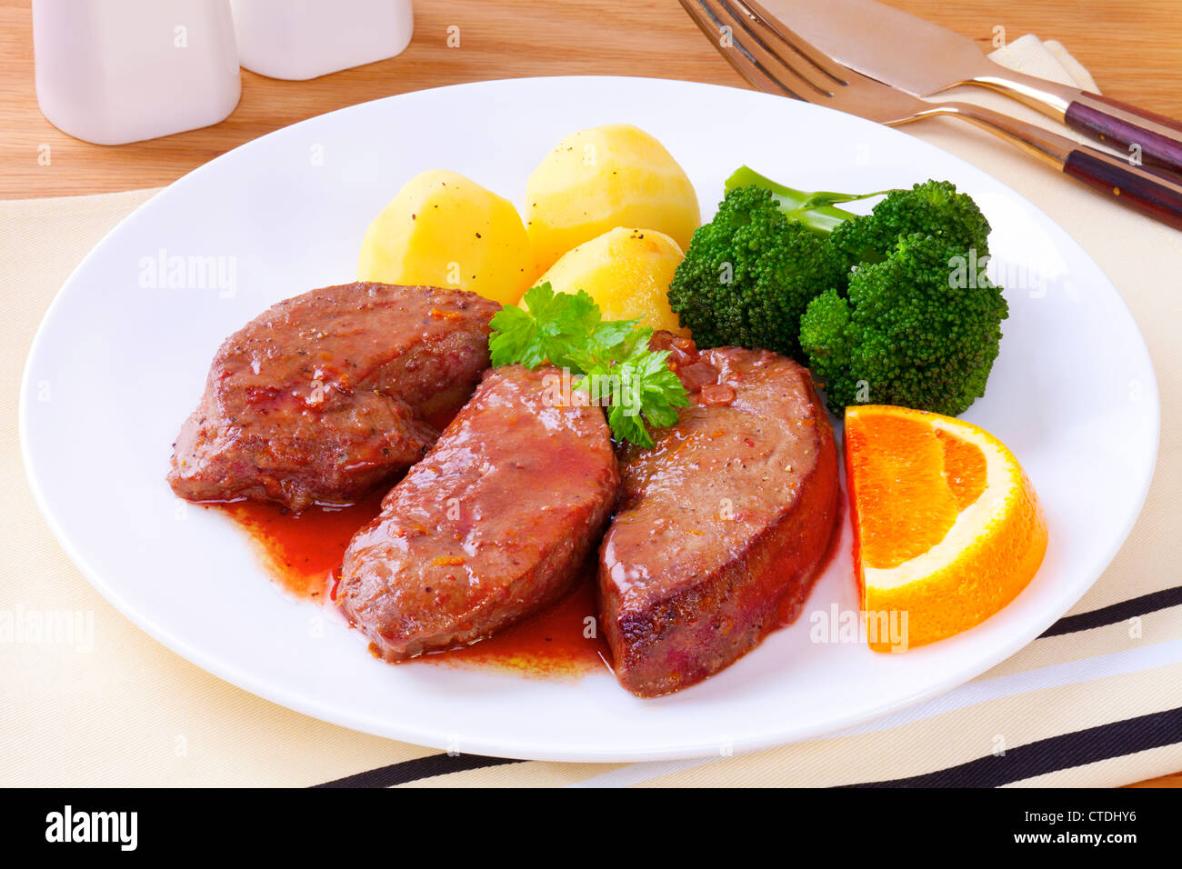 Lamb's liver or lamb fry, cooked in a sauce made from wine and orange, served with new potatoes and broccoli. Stock Photo
