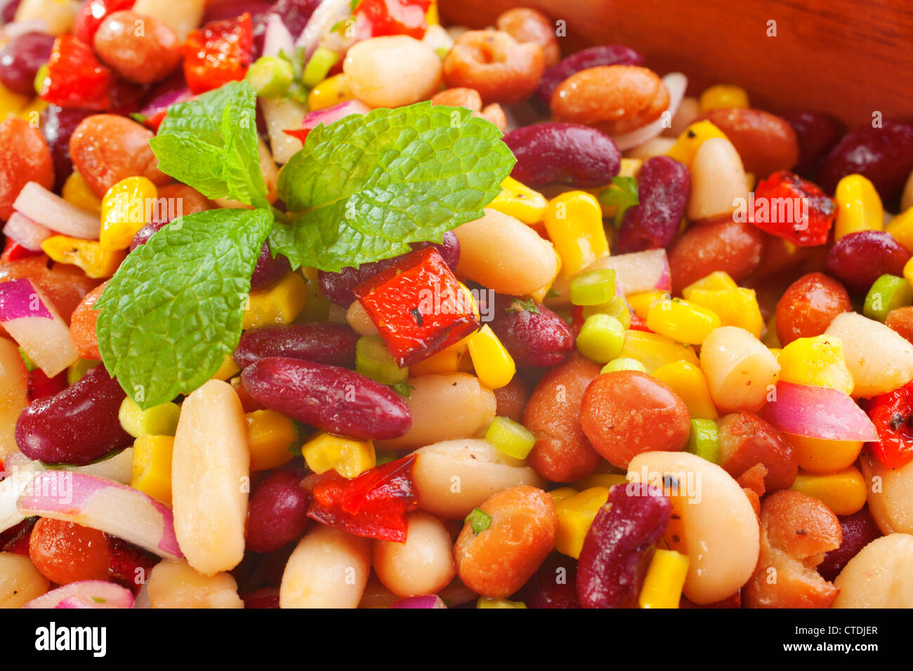 Three bean salad with sweetcorn, roasted red peppers and red onion in a vinaigrette dresing. Stock Photo