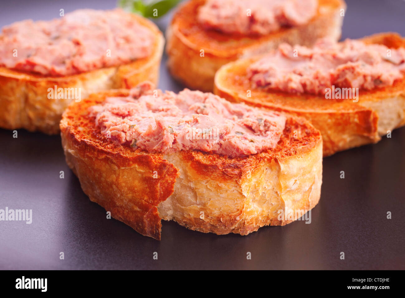 Pate on toasted baguette, on a black plate. Stock Photo