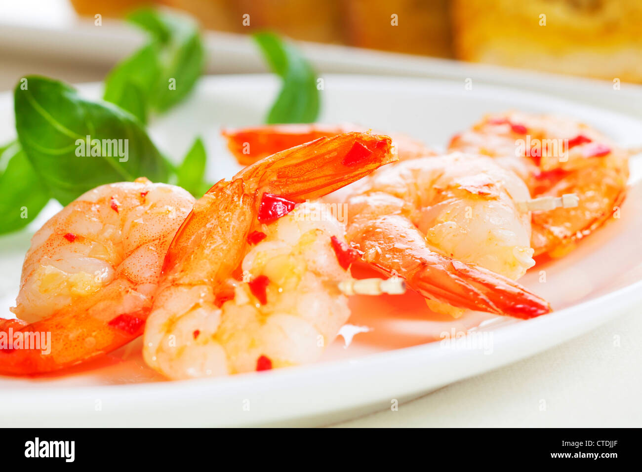 Prawns on skewers in garlic and chilli, with garlic bread. Stock Photo